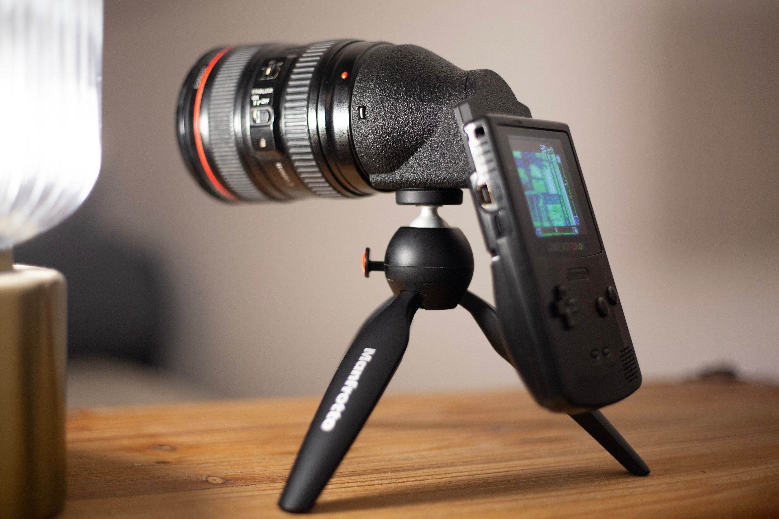 A Canon lens on the metal Game Boy Camera adapter, with a Game Boy Color on a small tripod